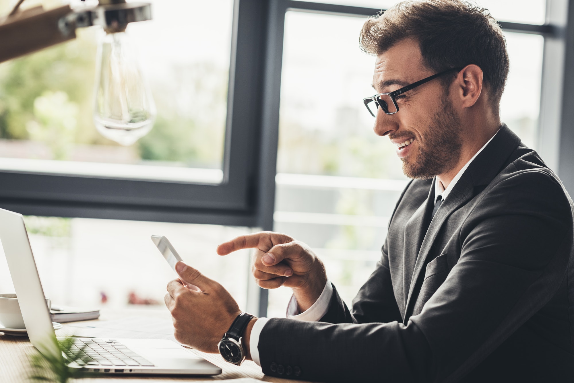 happy businessman using smartphone at workplace